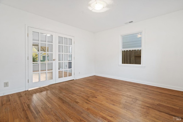 spare room with hardwood / wood-style flooring and french doors