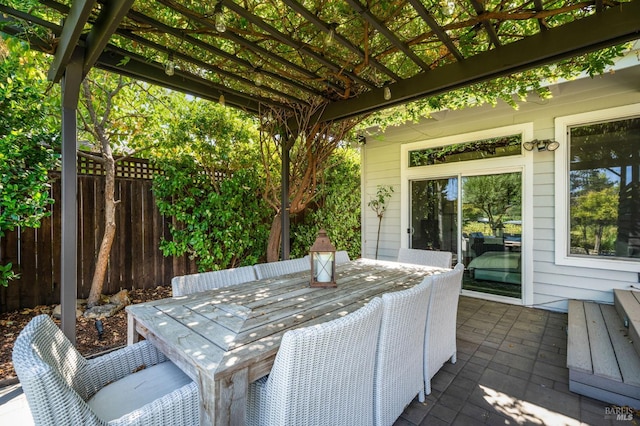 view of patio with outdoor dining space, fence, and a pergola