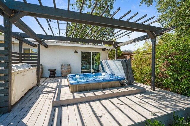 wooden terrace featuring hot tub deck surround and a pergola
