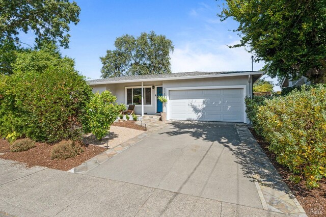 ranch-style house with a garage, driveway, and stucco siding