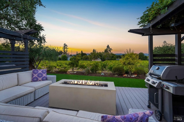 patio terrace at dusk featuring an outdoor living space with a fire pit, area for grilling, and a wooden deck