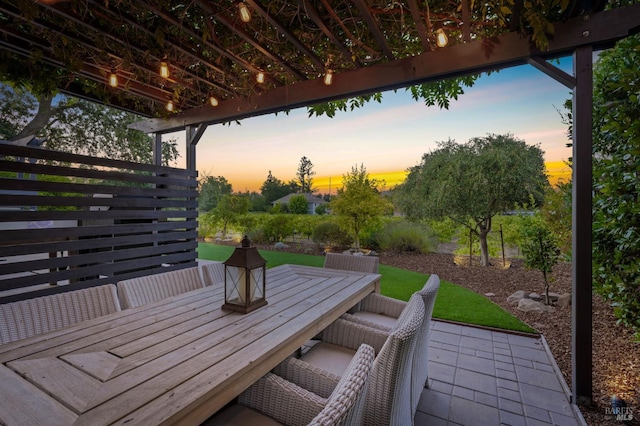 patio terrace at dusk featuring outdoor dining area and a wooden deck