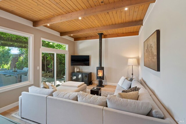 living room with a wood stove, light wood finished floors, beam ceiling, and wooden ceiling