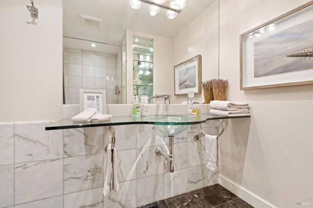 bathroom with a tile shower and marble finish floor