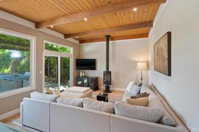 living room with light wood-type flooring, a wood stove, wood ceiling, and beamed ceiling