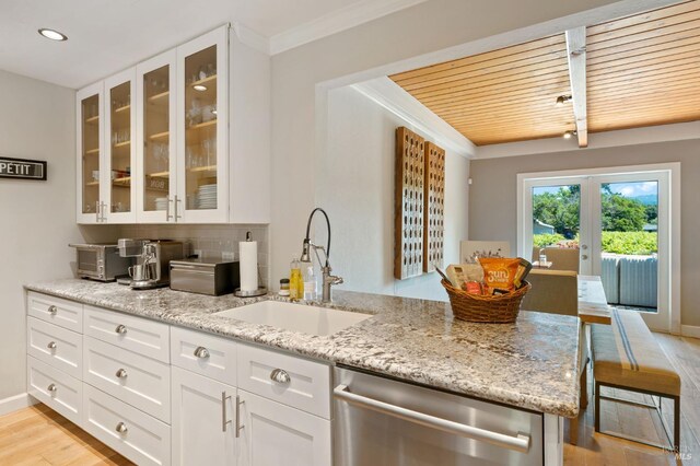 kitchen featuring light stone counters, sink, white cabinets, and stainless steel dishwasher