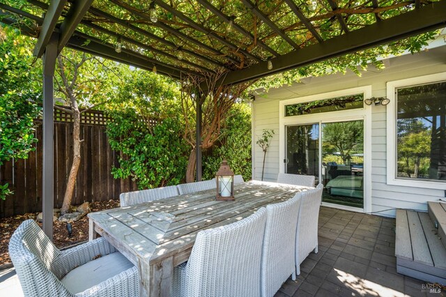 view of patio with a pergola, fence, and outdoor dining space