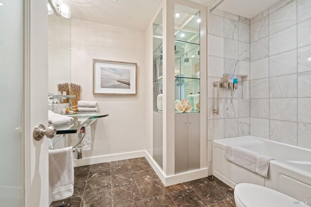 bathroom featuring baseboards, toilet, bathing tub / shower combination, and marble finish floor