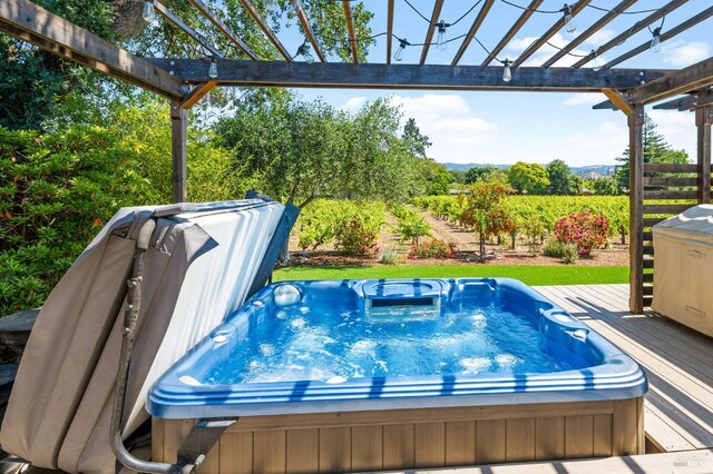 view of swimming pool with a wooden deck, a pergola, and a covered hot tub