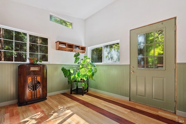 entryway with wood finished floors and a wainscoted wall