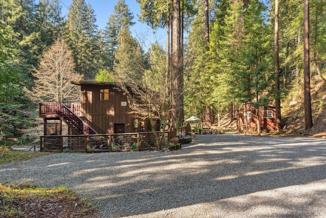 exterior space featuring stairway, a deck, and a wooded view