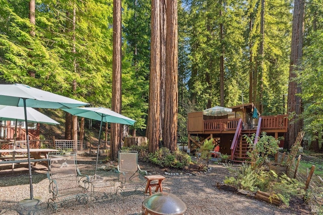 exterior space featuring a wooden deck, fence, stairs, and a view of trees