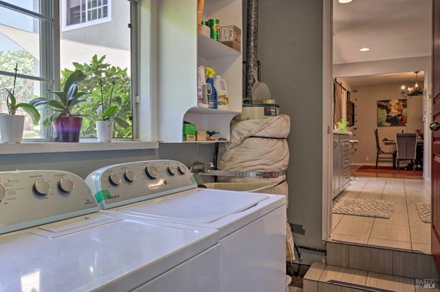 clothes washing area with an inviting chandelier, sink, washing machine and dryer, and a wealth of natural light