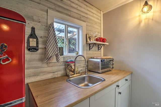 kitchen featuring white cabinetry, sink, and refrigerator