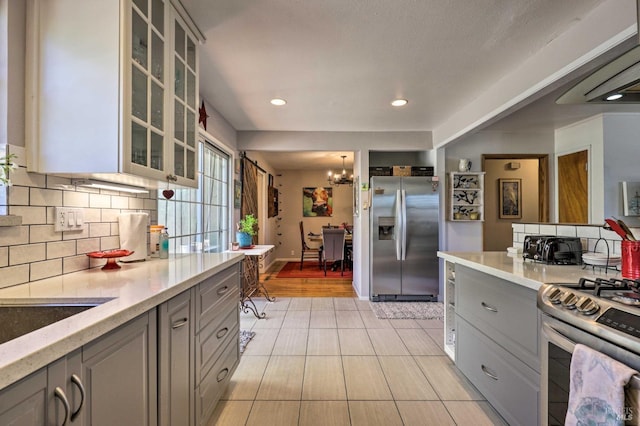 kitchen featuring a notable chandelier, stainless steel appliances, decorative backsplash, and gray cabinetry