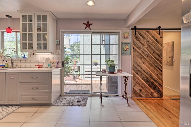 doorway featuring light tile patterned flooring, a barn door, sink, and a wealth of natural light