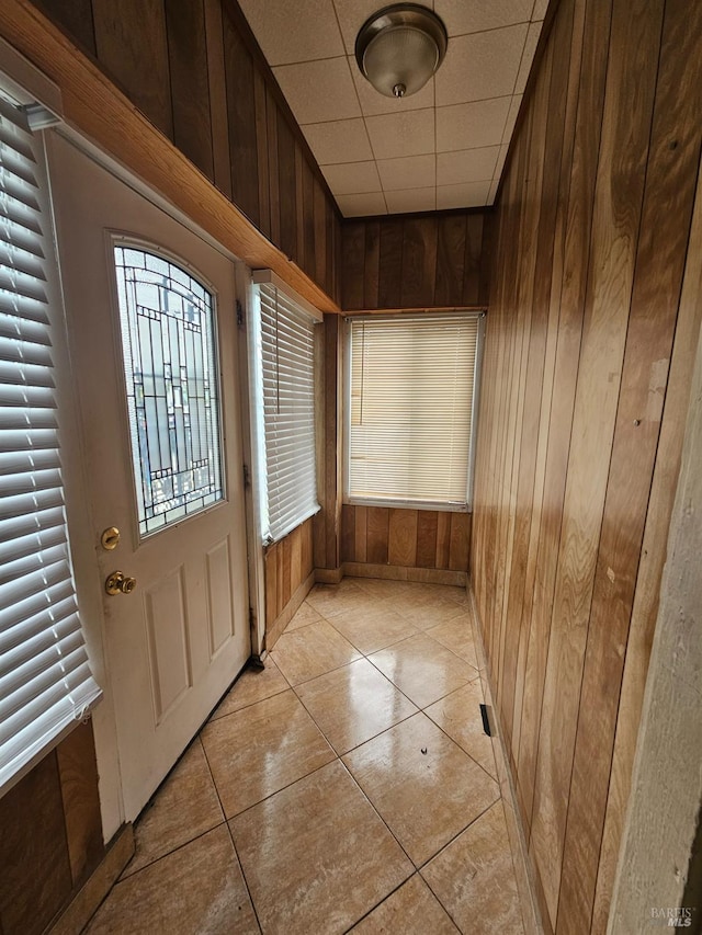 entryway with light tile patterned flooring and wood walls