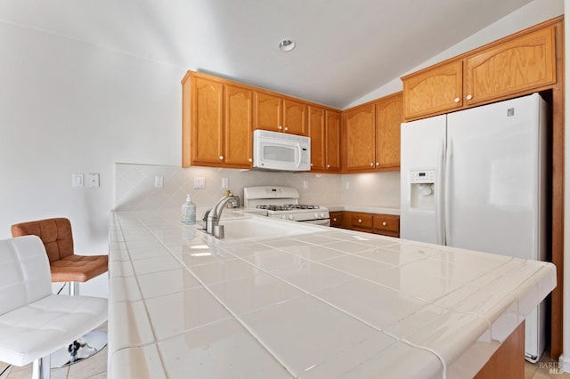 kitchen with kitchen peninsula, white appliances, lofted ceiling, and tile counters