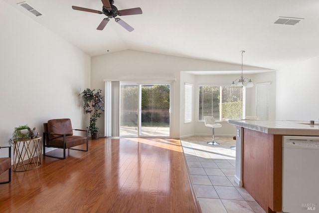 living room featuring lofted ceiling, a healthy amount of sunlight, ceiling fan with notable chandelier, and light hardwood / wood-style floors