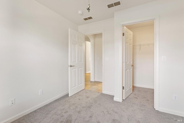 unfurnished bedroom with light colored carpet and a spacious closet