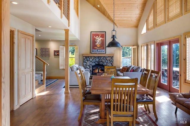 dining space with high vaulted ceiling, dark hardwood / wood-style floors, a stone fireplace, and wooden ceiling