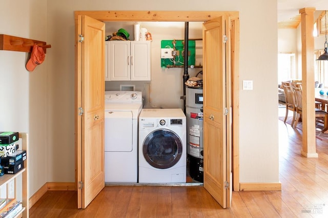 laundry room with light hardwood / wood-style flooring, water heater, independent washer and dryer, and cabinets