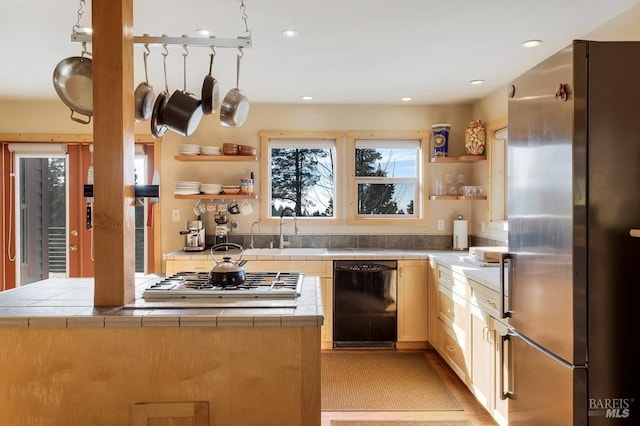 kitchen with kitchen peninsula, appliances with stainless steel finishes, tile counters, light brown cabinetry, and sink