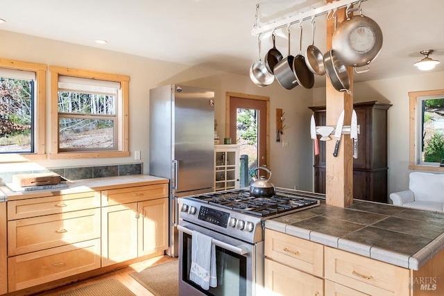 kitchen featuring a wealth of natural light, stainless steel appliances, light brown cabinets, and tile counters