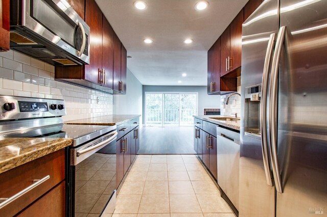 kitchen with light stone counters, appliances with stainless steel finishes, light tile patterned flooring, and sink