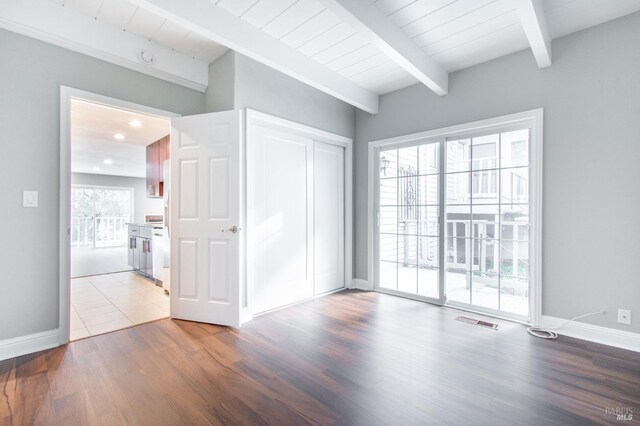 unfurnished room with plenty of natural light, wood ceiling, beam ceiling, and light hardwood / wood-style floors