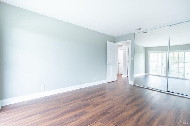 unfurnished bedroom with dark wood-type flooring and a closet