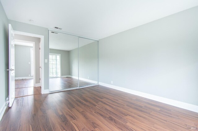 unfurnished bedroom with dark wood-type flooring and a closet