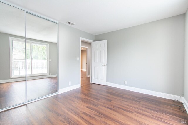 unfurnished bedroom featuring dark hardwood / wood-style floors and a closet