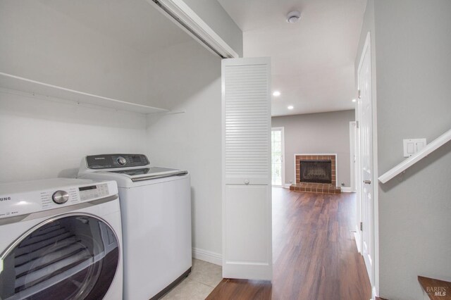 laundry area with washing machine and dryer, hardwood / wood-style floors, and a fireplace