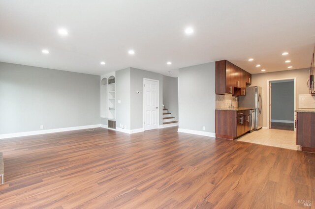 unfurnished living room featuring dark wood-type flooring and built in features