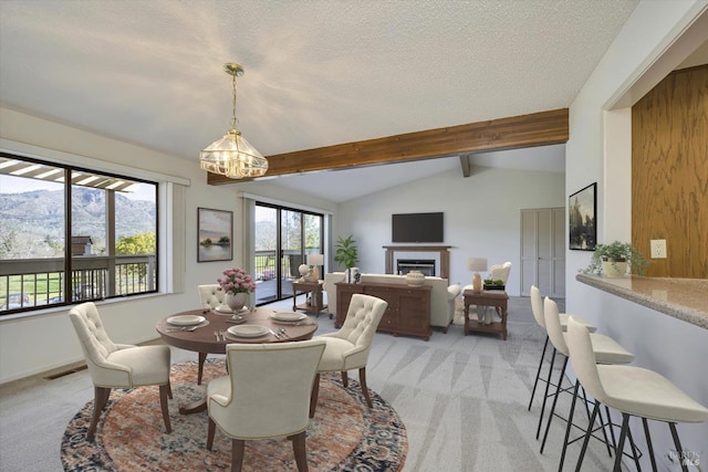 dining area featuring lofted ceiling with beams, a textured ceiling, light colored carpet, visible vents, and a glass covered fireplace