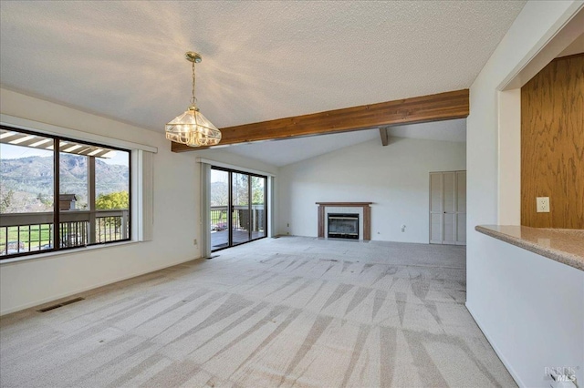 unfurnished living room featuring visible vents, lofted ceiling with beams, a glass covered fireplace, light carpet, and a textured ceiling