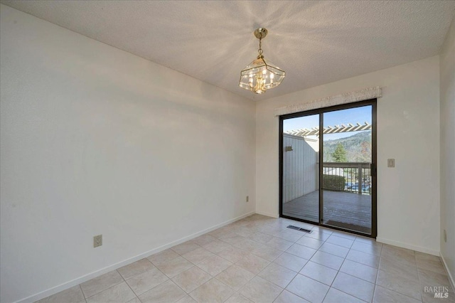 unfurnished room with a chandelier, visible vents, a textured ceiling, and baseboards