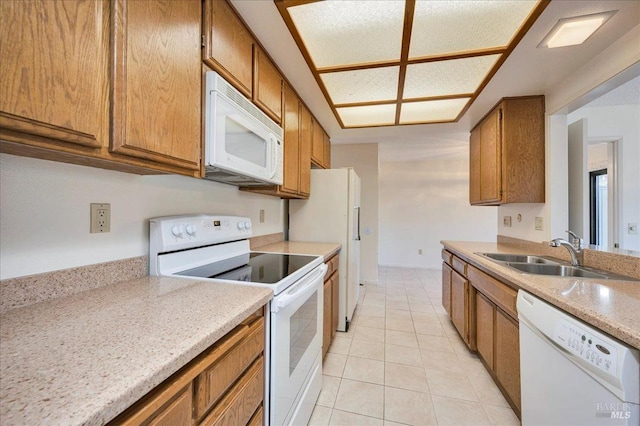 kitchen with light countertops, white appliances, brown cabinets, and a sink