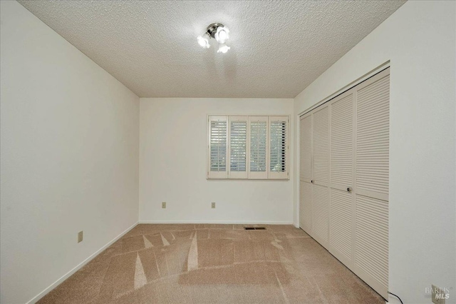 unfurnished bedroom featuring a closet, visible vents, light carpet, and baseboards