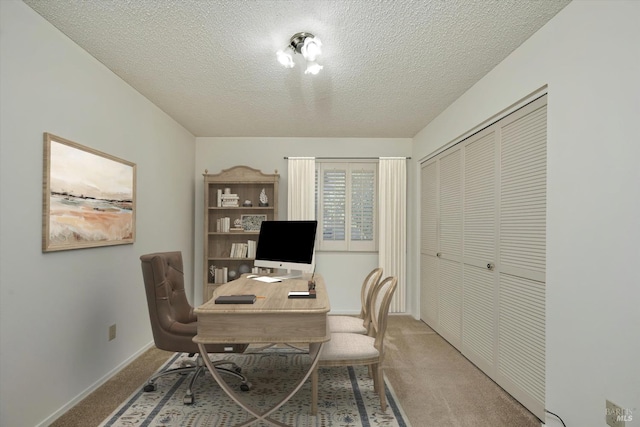 carpeted office space featuring a textured ceiling and baseboards