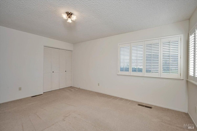 unfurnished bedroom with carpet, multiple windows, visible vents, and a closet