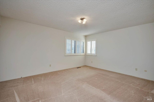 spare room with a textured ceiling, carpet floors, and visible vents