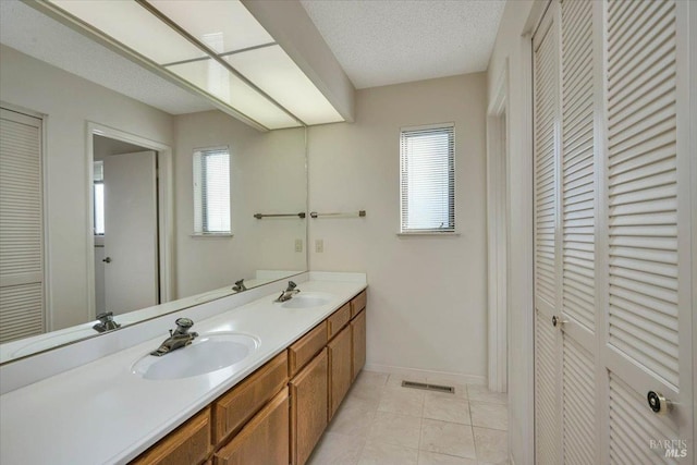 bathroom with tile patterned flooring, a closet, visible vents, and a sink