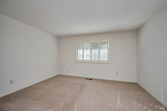 spare room with visible vents, carpet flooring, and a textured ceiling