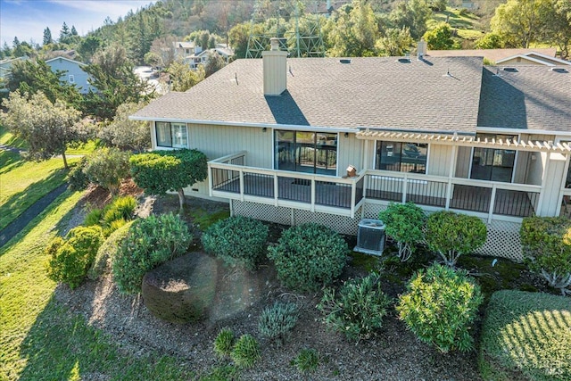 rear view of property with a chimney, a shingled roof, central AC unit, a deck, and a pergola