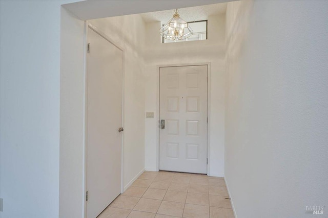 doorway to outside with light tile patterned floors, baseboards, and an inviting chandelier