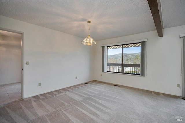 empty room with light carpet, beam ceiling, visible vents, and a textured ceiling