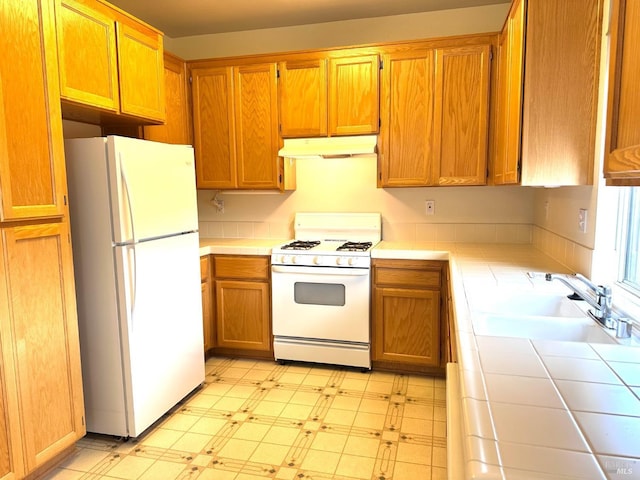 kitchen with tile counters, white appliances, and sink