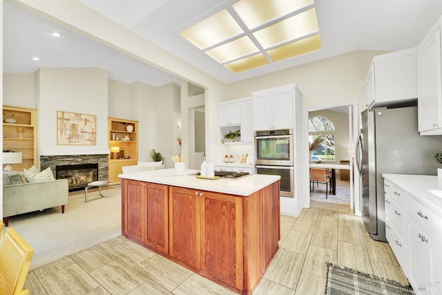 kitchen with light carpet, a fireplace, stainless steel appliances, white cabinets, and a kitchen island